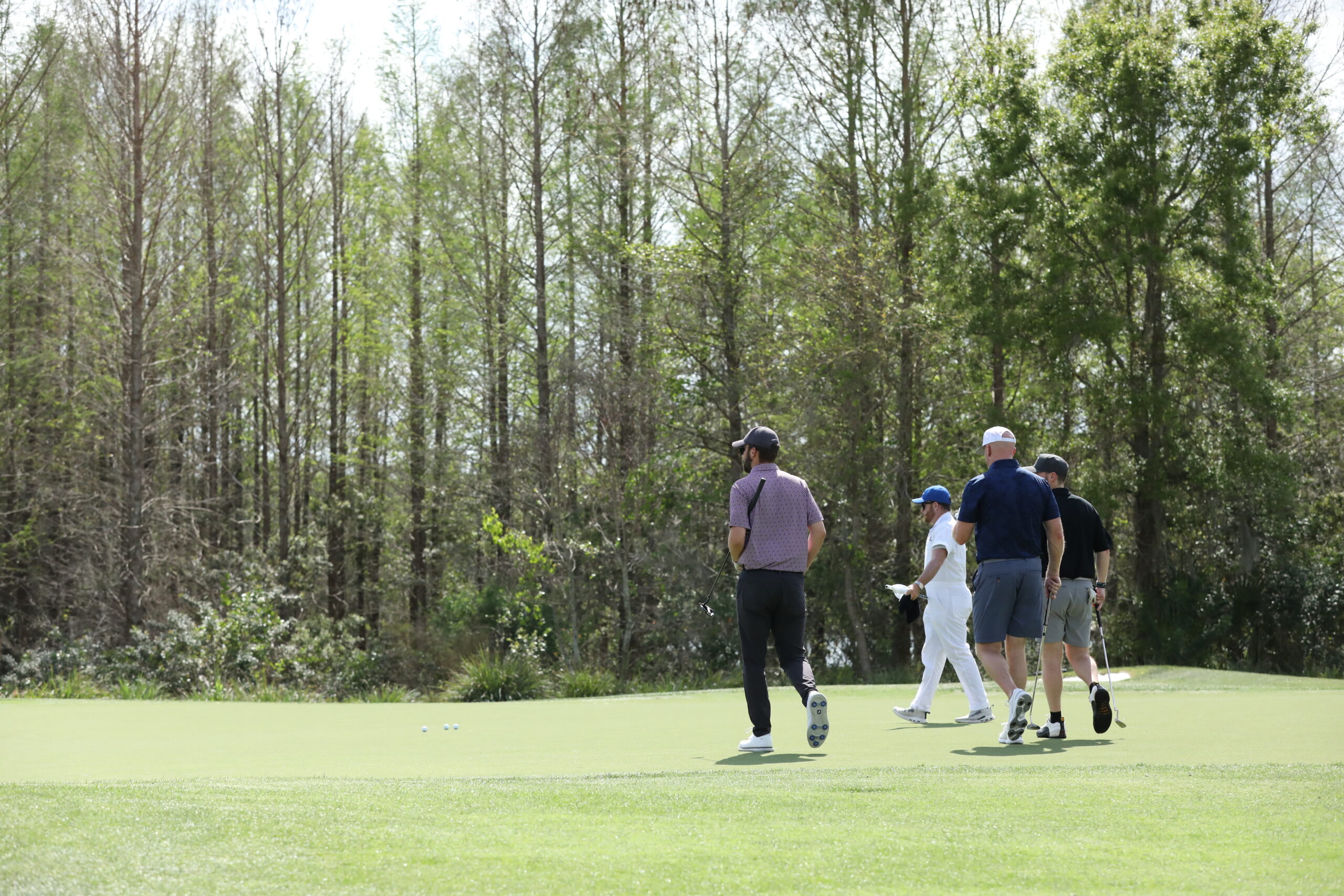 men heading towards trees with golf clubs