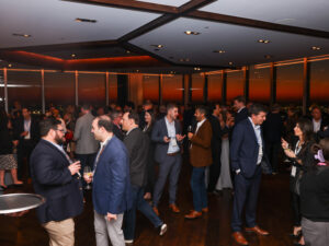 a room packed with men and women networking in business attire