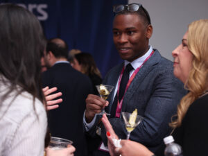 man speaking to two women over martinis, more people in the back